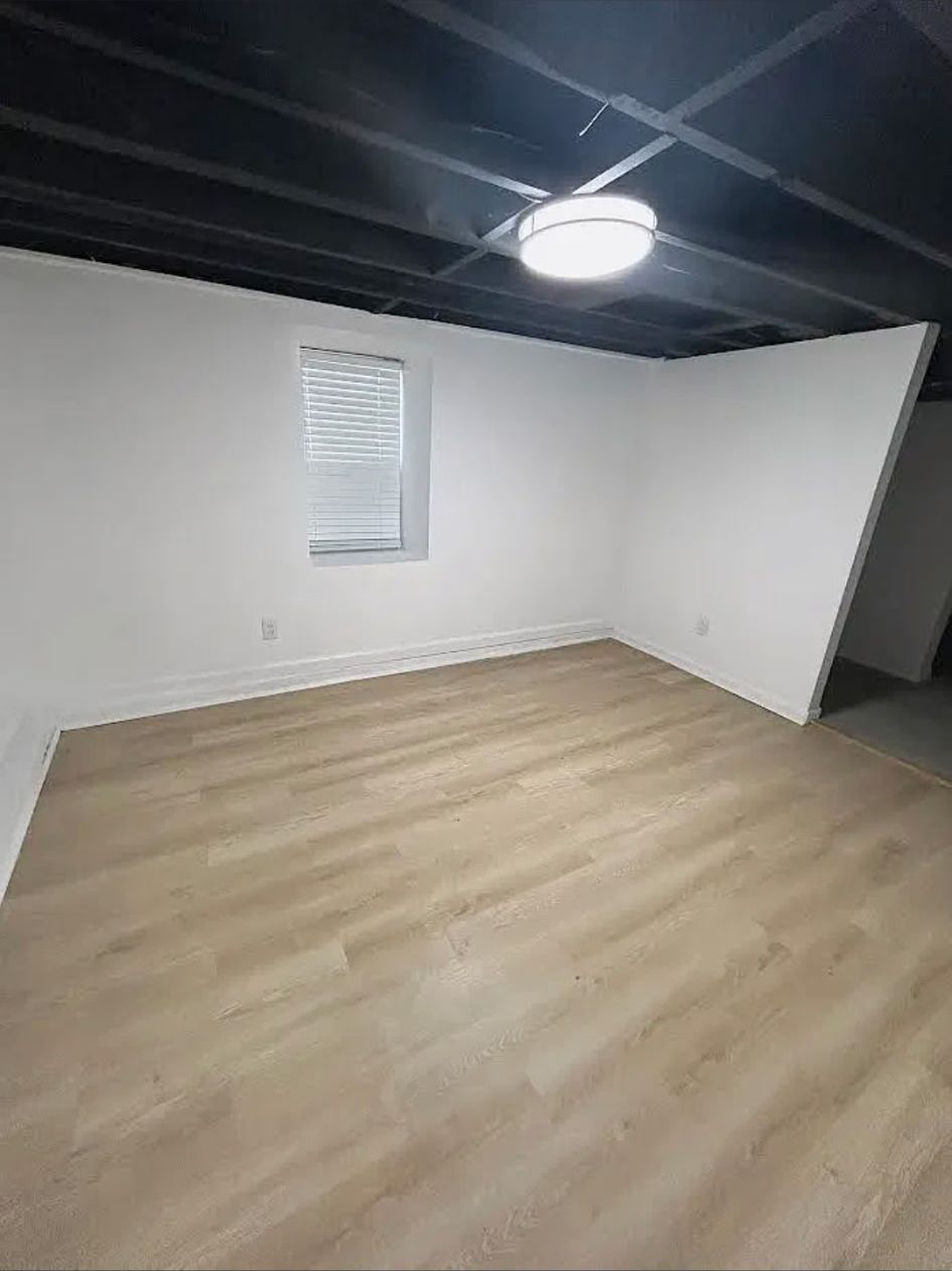 Large basement bedroom with new flooring and a window